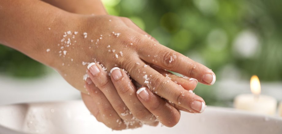 Hände, die sich mit einer Peeling-Creme eincremen.
